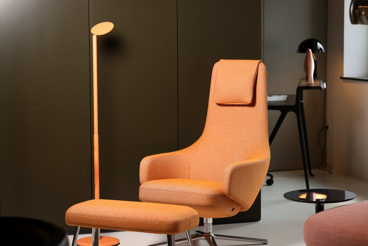 Oranger Designsessel mit Hocker und Stehleuchte vor dunkelgruener Schrankwand — Das Studiozwei, Werbefotograf München