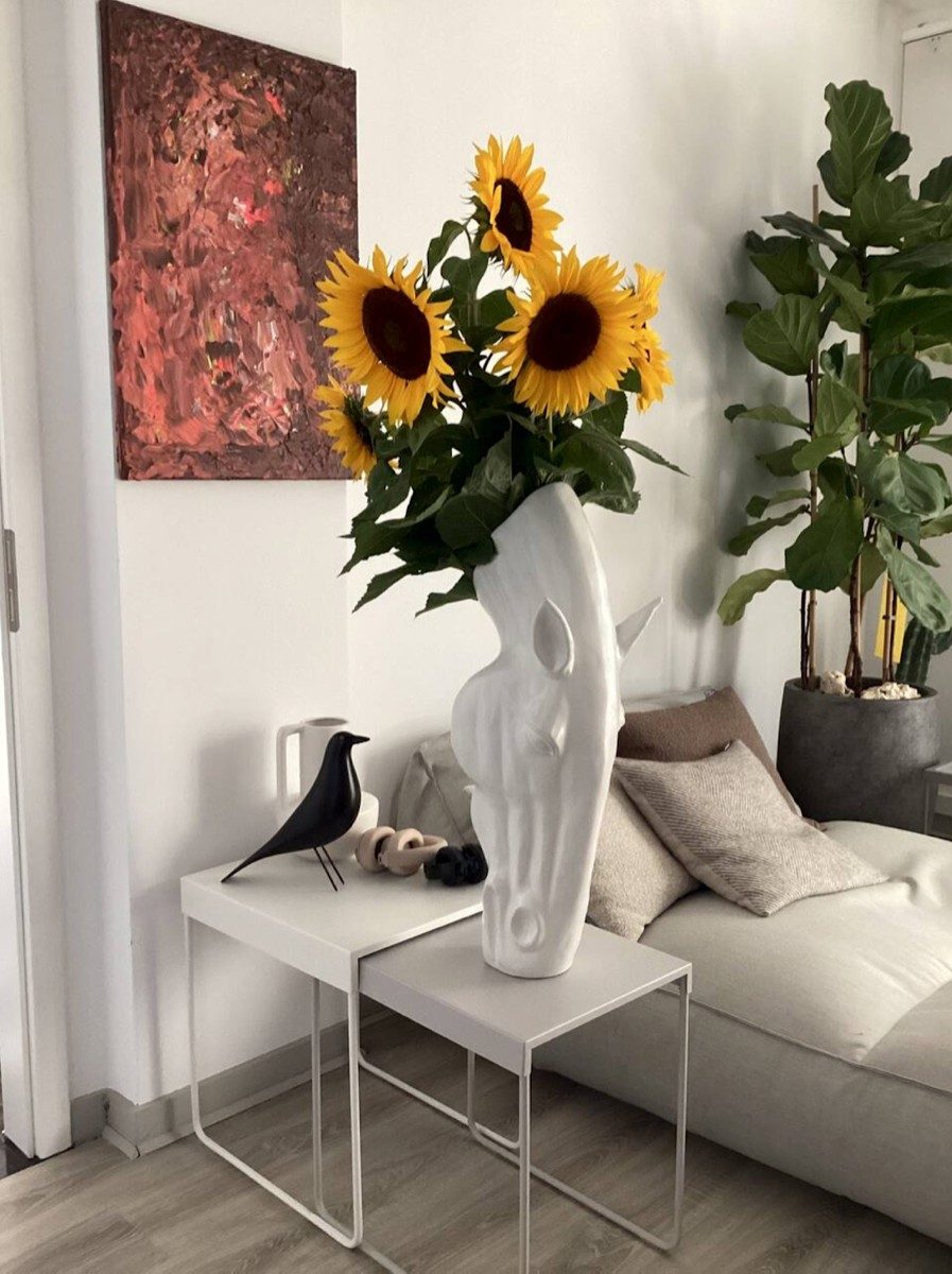 Wohnzimmerecke mit heller Couch, Designvase mit Sonnenblumen und abstraktem Wandbild — Das Studiozwei, Werbefotograf München