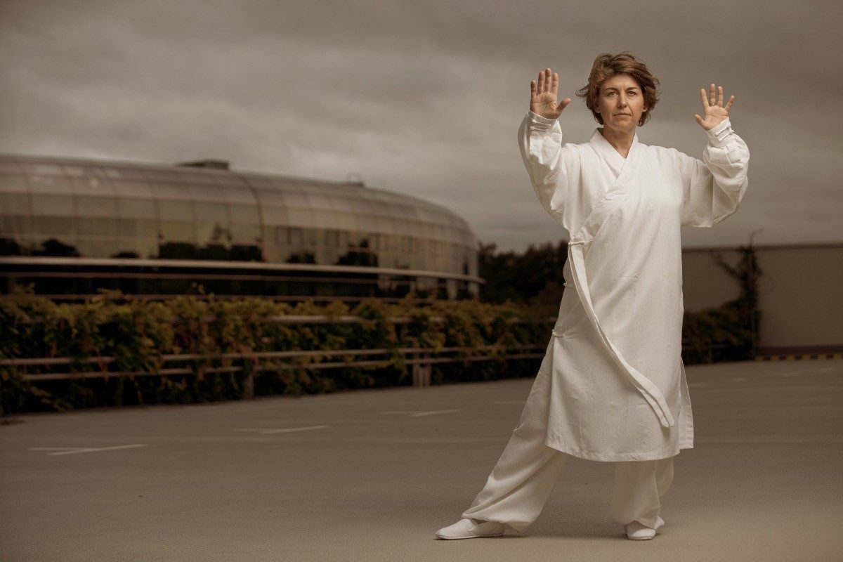 Frau in weissem Gewand in Tai-Chi-Haltung auf einem leeren Parkdeck vor Wolkenhimmel — Das Studiozwei, Werbefotograf München