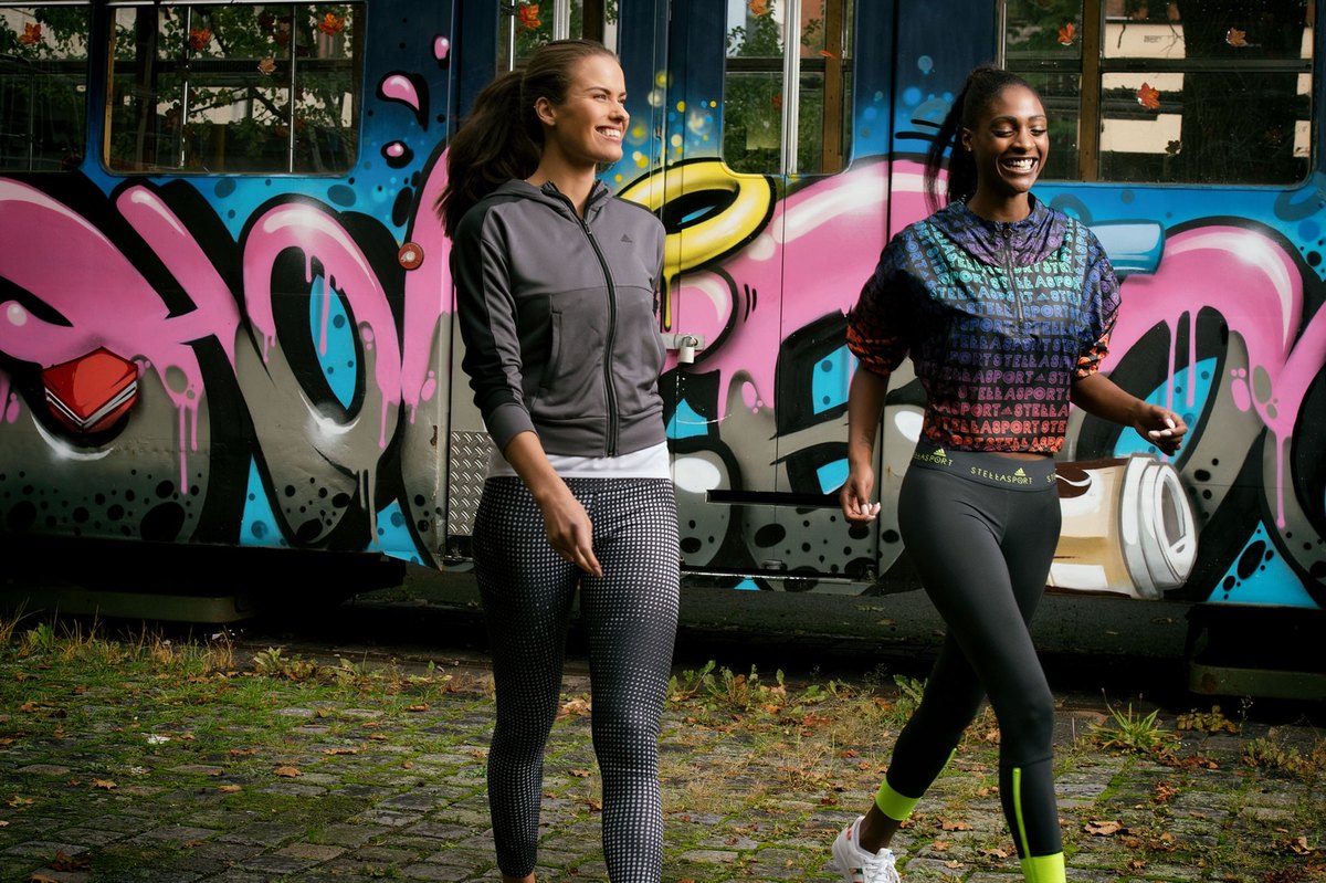 Zwei laufende Frauen in Sportkleidung vor einer graffitibespruehten Strassenbahn — Das Studiozwei, Werbefotograf München