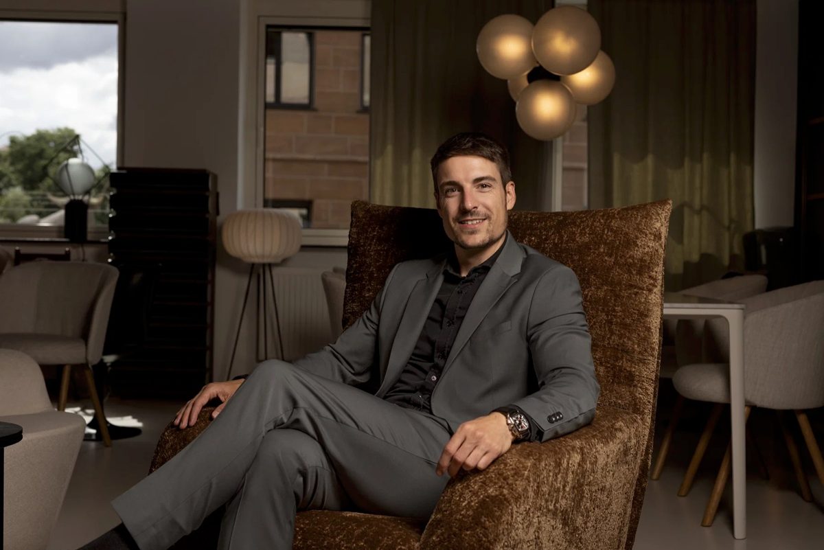 Businessportrait eines Mannes im grauen Anzug, sitzend in einem braunen Samtsessel in einer Lounge — Das Studiozwei, Werbefotograf München