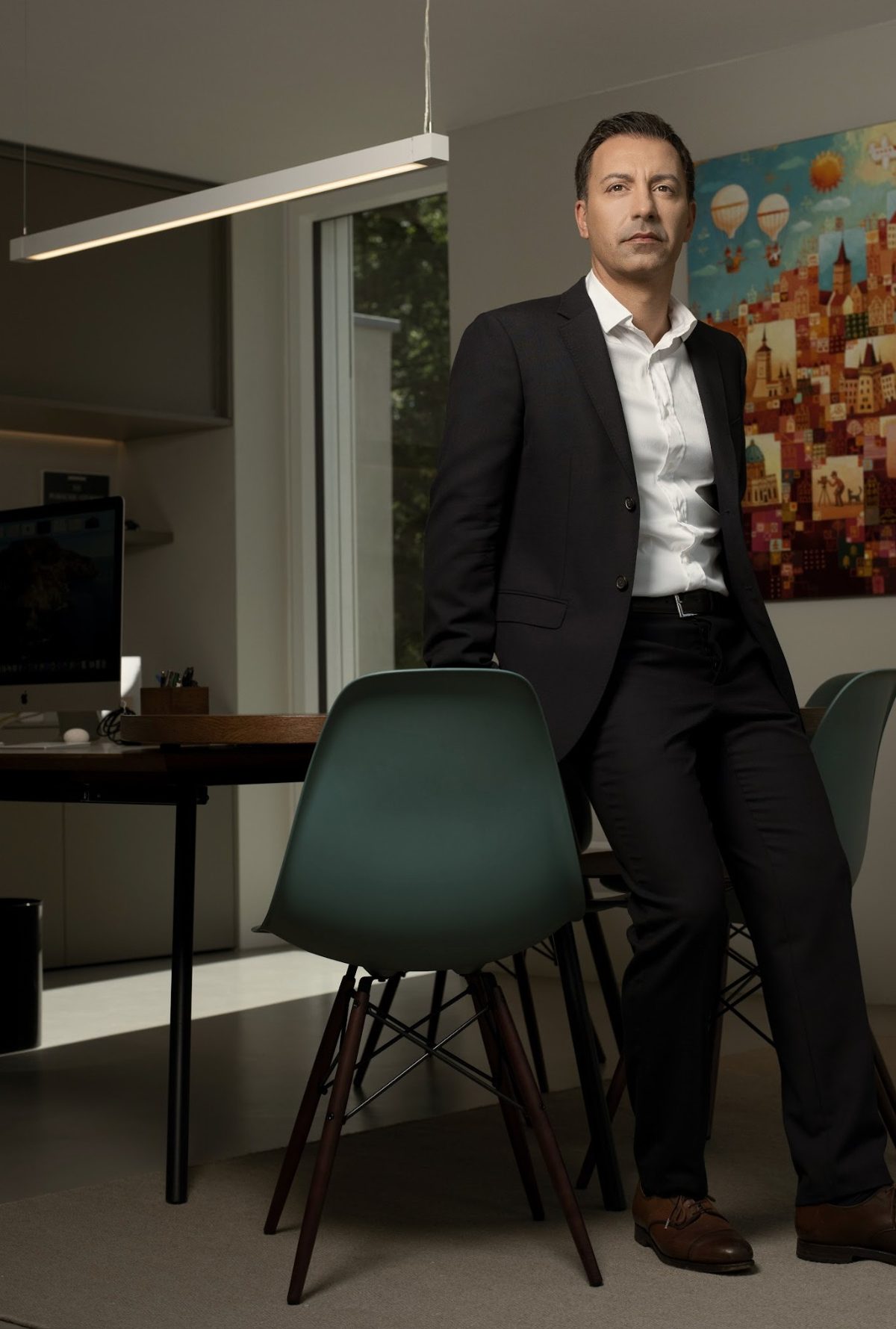 Businessportrait eines Mannes im schwarzen Anzug in einem modernen Buero mit gruenen Stuehlen — Das Studiozwei, Werbefotograf München