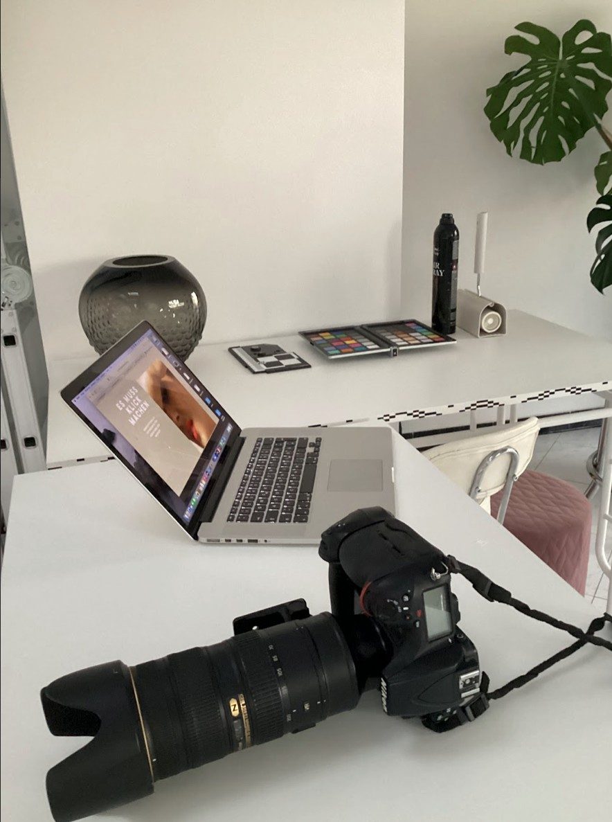 Kamera mit Teleobjektiv und Laptop mit Beautybild auf einem weissen Studiotisch — Das Studiozwei, Werbefotograf München