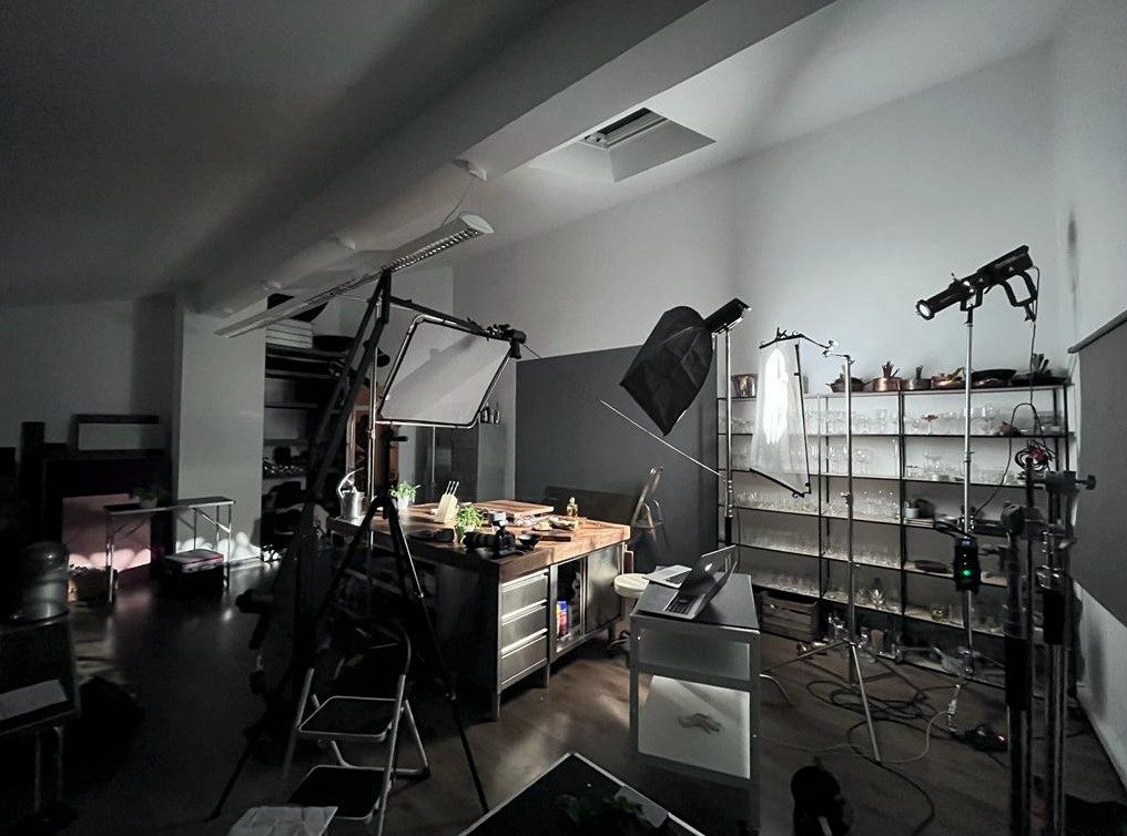 Studioraum mit beleuchtetem Aufnahmetisch, Lichtformern und Requisitenregal — Das Studiozwei, Werbefotograf München